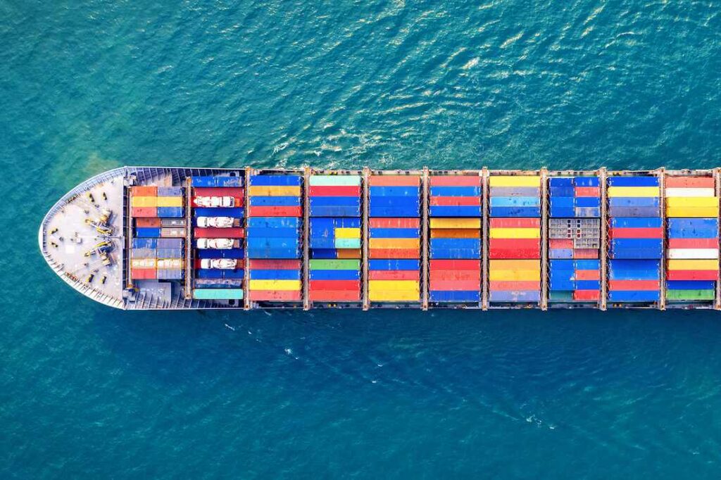 Un enorme barco carguero lleno de contenedores coloridos surca el océano para exportar productos a otro país, donde se enfrentarán a los aranceles y otras barreras comerciales a la exportación